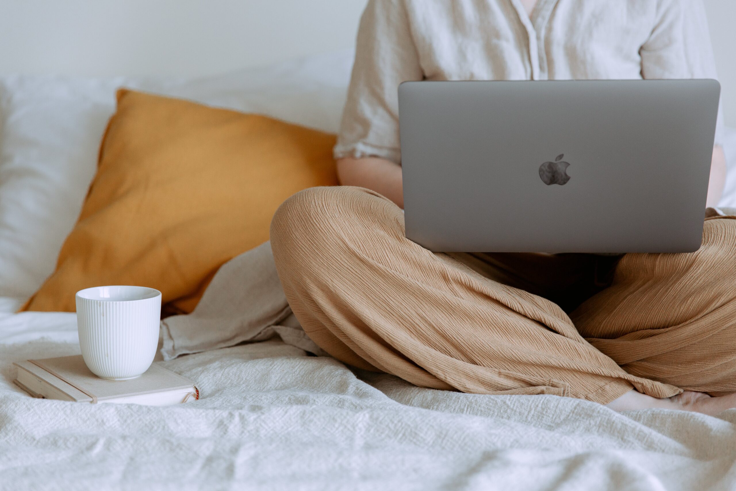 lady sitting on bed with laptop and coffee